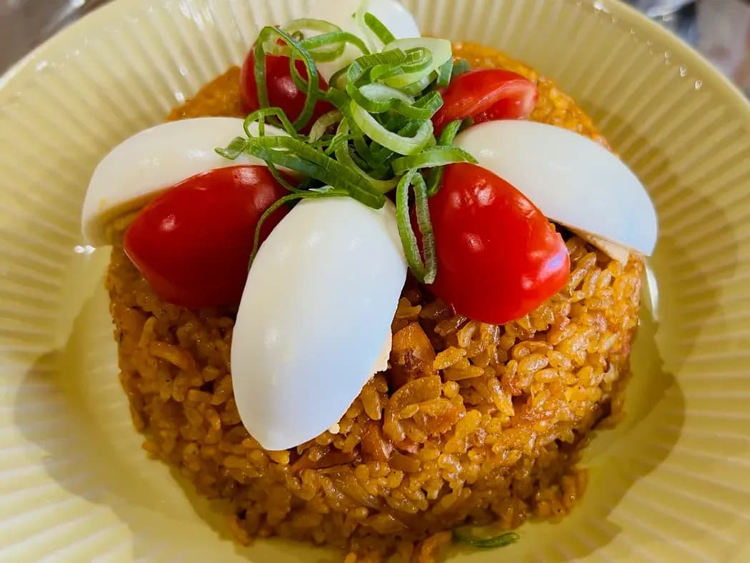Biryani topped with boiled egg, cherry tomato and spring onion