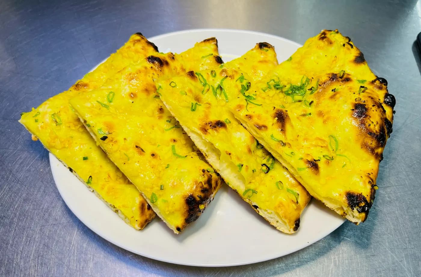 Garlic naan, sliced and topped with spring onion