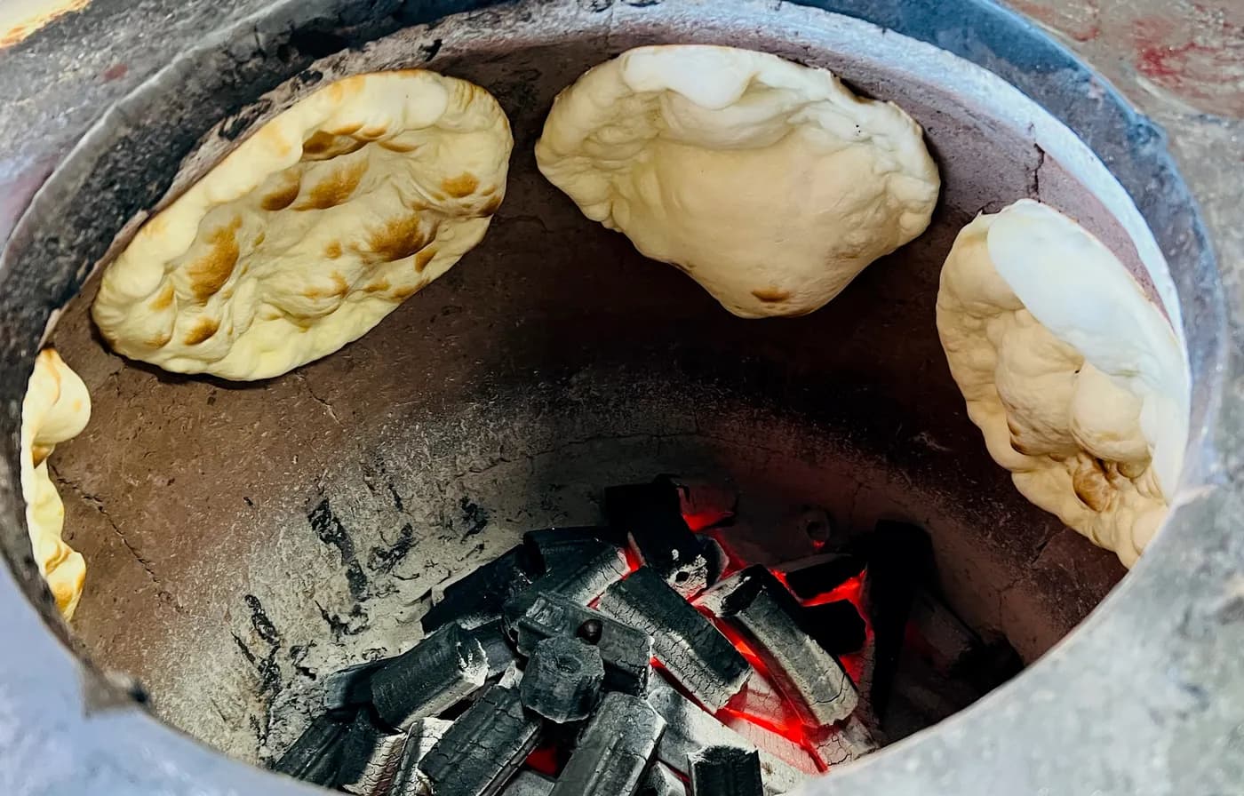 Naan baking against the wall of the charcoal tandoor oven