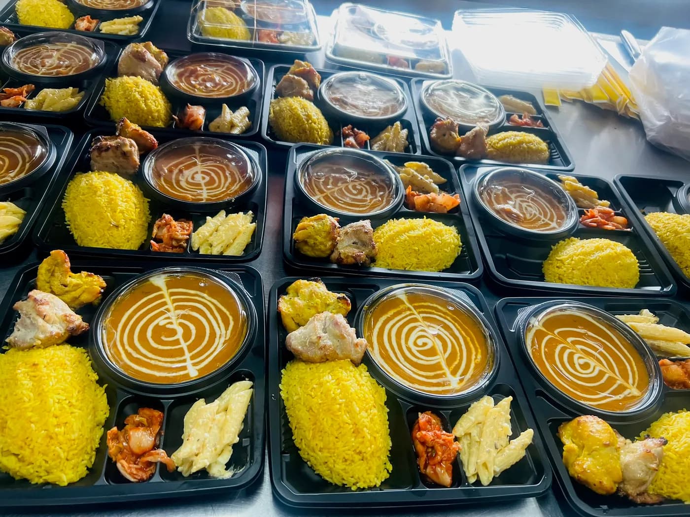 テーブルに並べられた、サフランライス、カレー、タンドリーチキン入りのお弁当